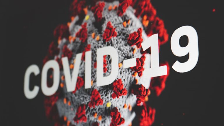 Bild på en förstoring av Covid virus med text Covid-19