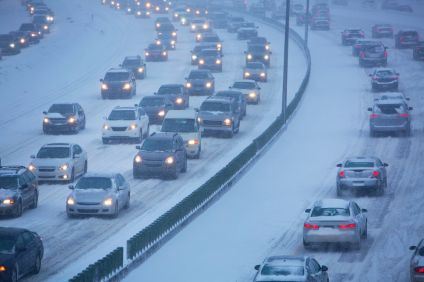 Bilar kö på motorväg i snöväglag. Det är skymning och snön faller.