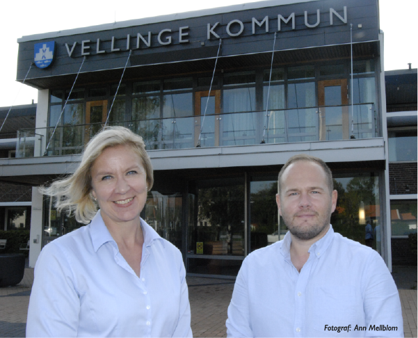 Annica Carlstedt och Philip Allgoth från Näringslivsenheten, iklädda matchande ljusblå skjortor, står utanför kommunhuset i Vellinge. 