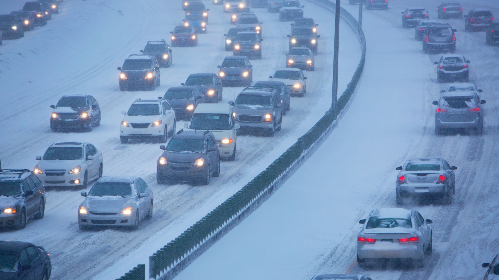 Bilar kö på motorväg i snöväglag. Det är skymning och snön faller.