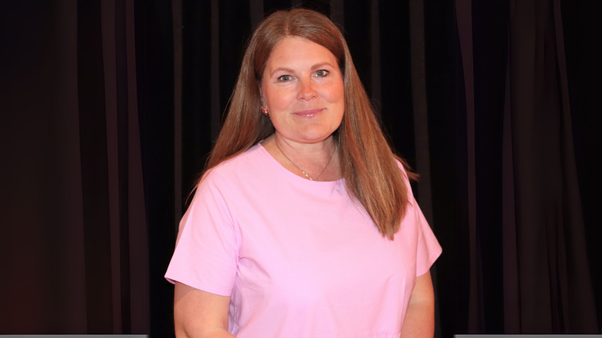 Kvinna i långt rödbrunt hår med rosa tröja.